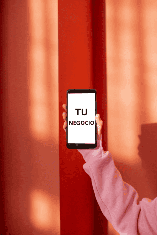 Marketing digital brazo sujeta telefono sobre fondo rojo, texto en pantalla "TU NEGOCIO"